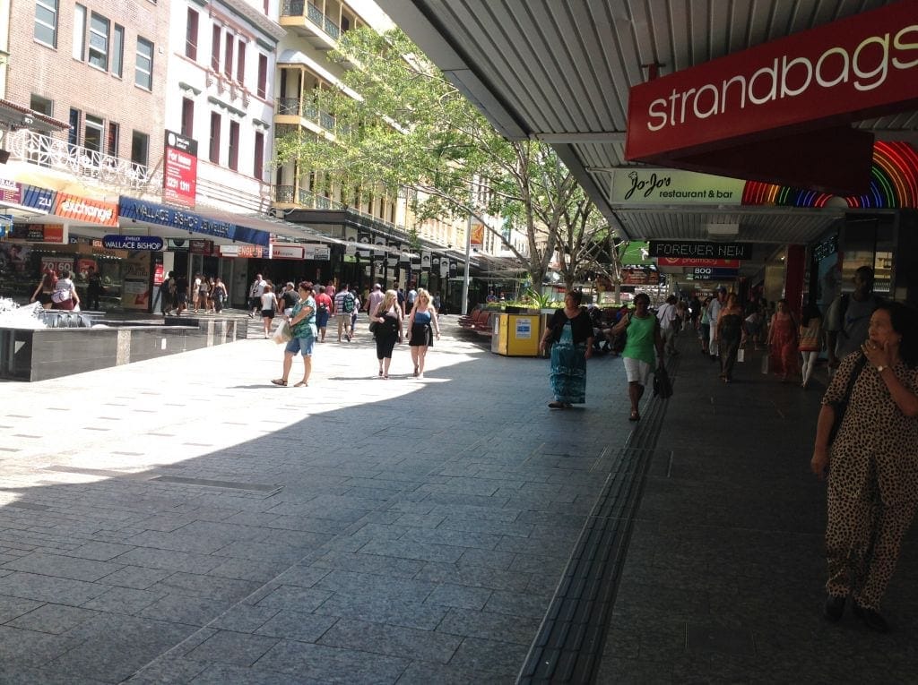 image in queen street mall, in front of standbags. many people walking  around.