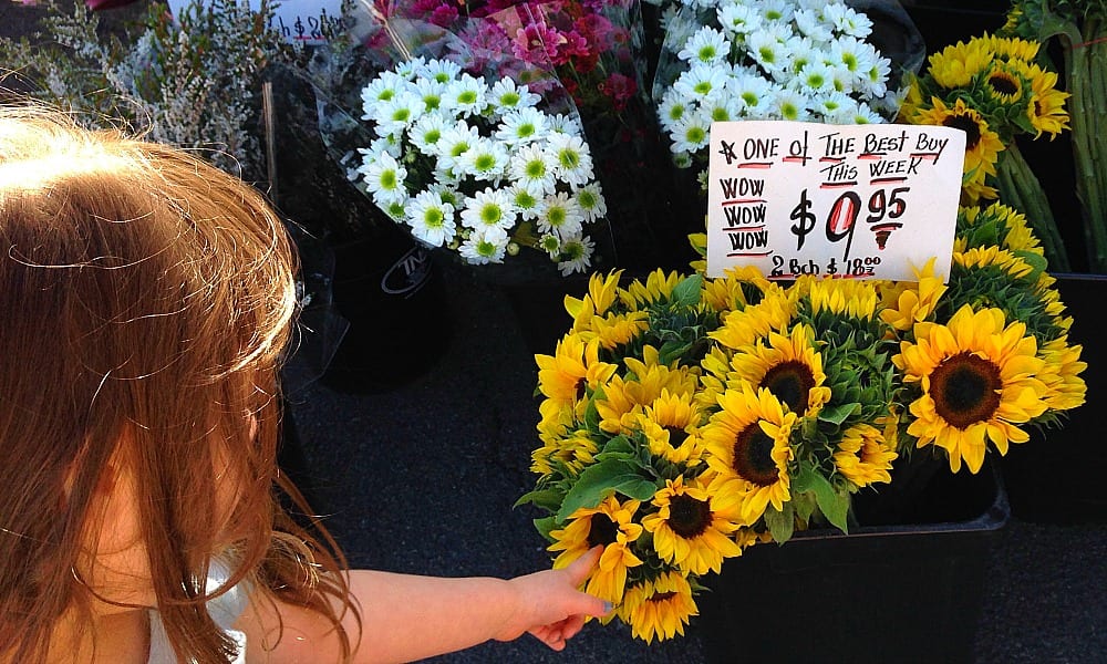 girl points at fresh flowers at Bundall Farmer's Market for Kids