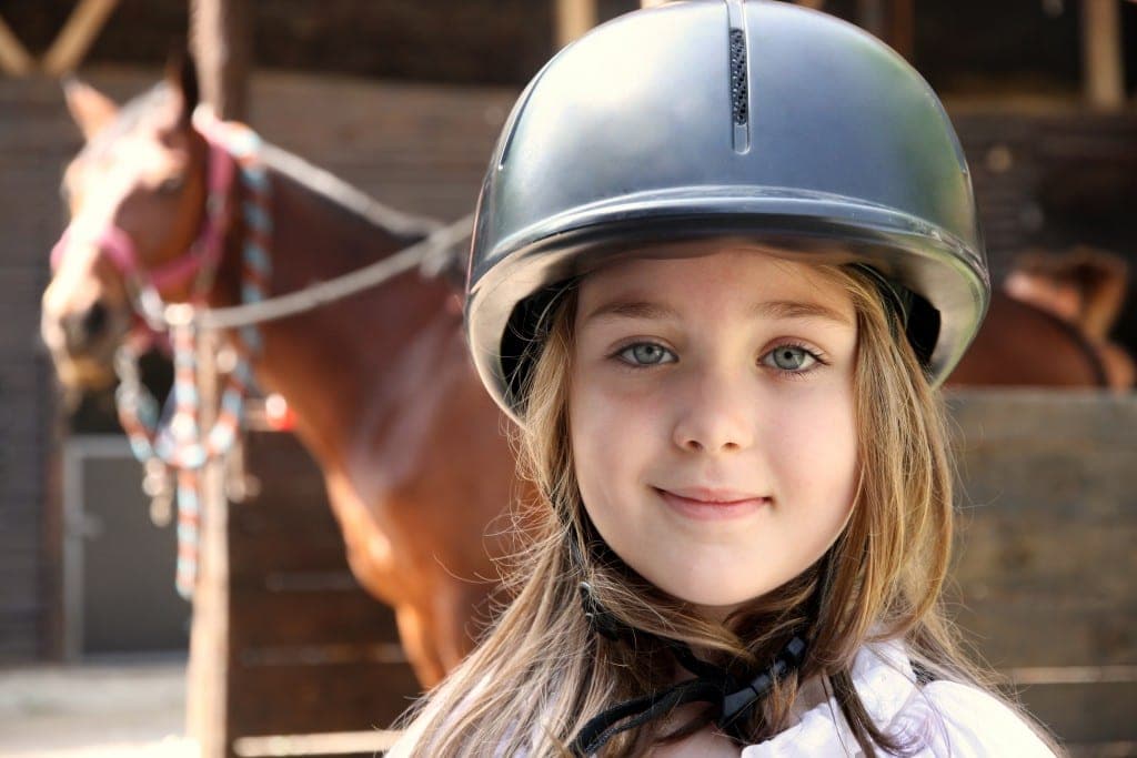 young girl in foreground with blurry horse in the background