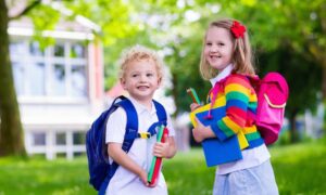 best lunch boxes Child going to school. Boy and girl holding books and pencils on the first school day. Little students excited to be back to school. Beginning of class after vacation. Kids eating apple in school yard