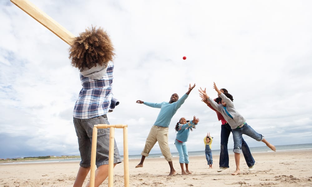 Family playing cricket on beach