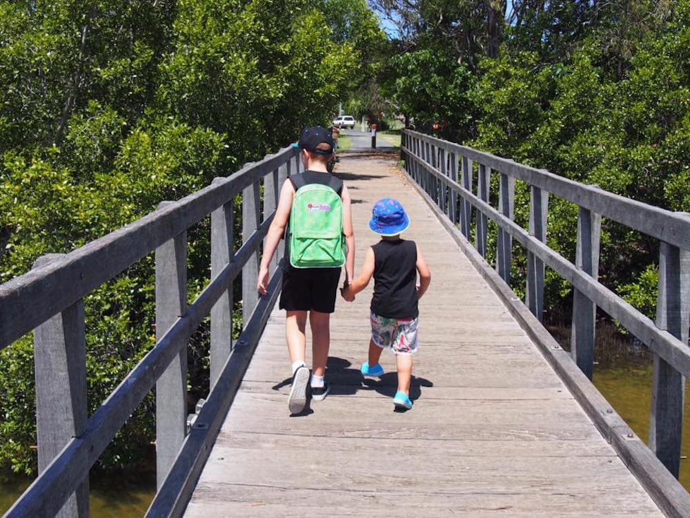 Two young brothers walking across foot bridge in Brunswick Heads