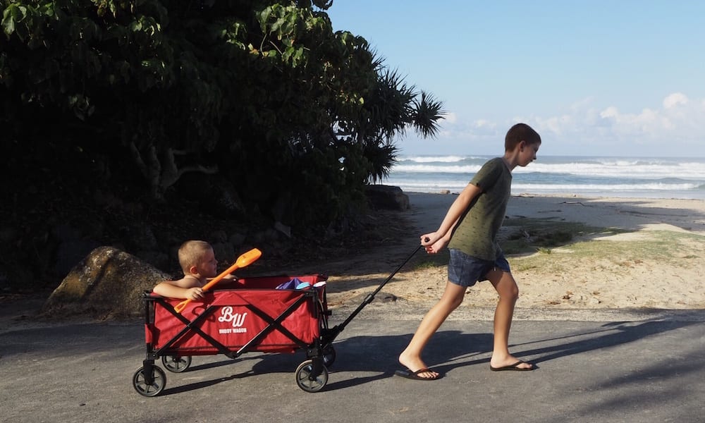 Brother dragging toddler in red Buddy Wagon