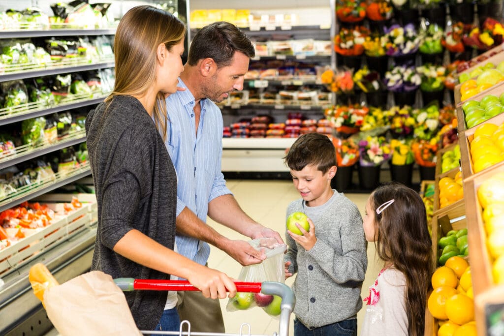 Boy counts apples into bag while grocery shopping