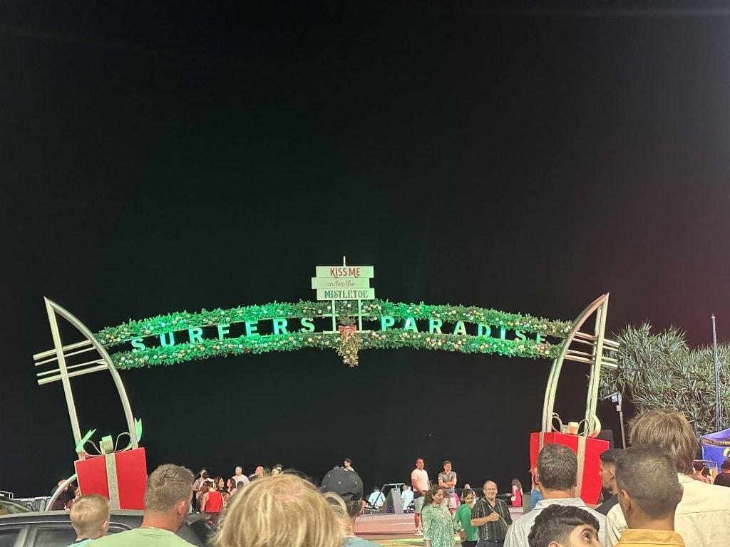 Surfers Paradise beach arch decorated for Christmas at night with crowds of people during Schoolies on the Gold Coast