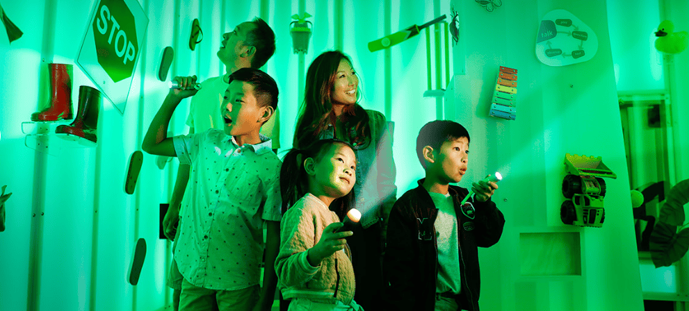 Family of children and adults use special torches to investigate light-play in Queensland Museum's Sparklab