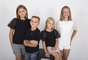 Silver kids’ necklaces with heart, peace-symbol and circle charms on a soft felt background with a white daisy”