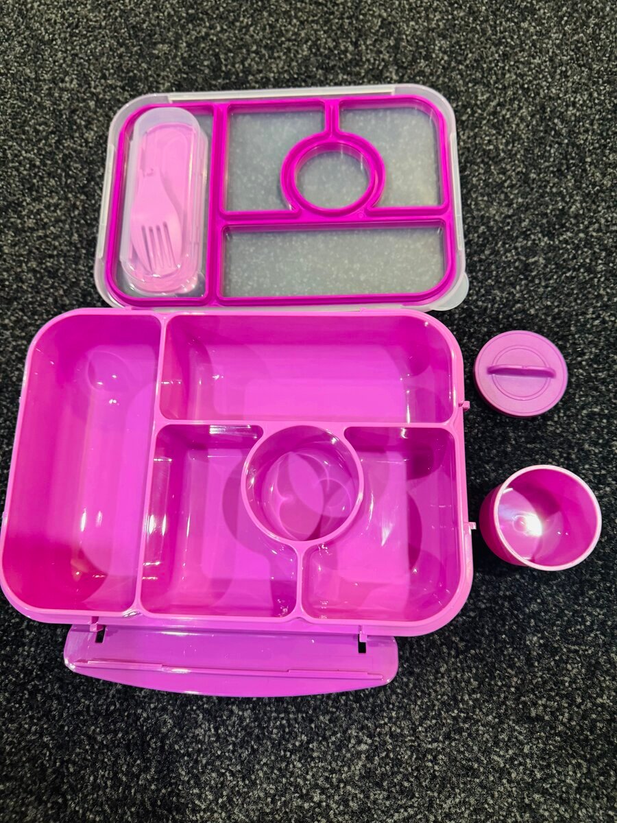 Open purple kids’ bento lunch box showing five compartments, removable sauce cup, and fork-spoon set in the lid.