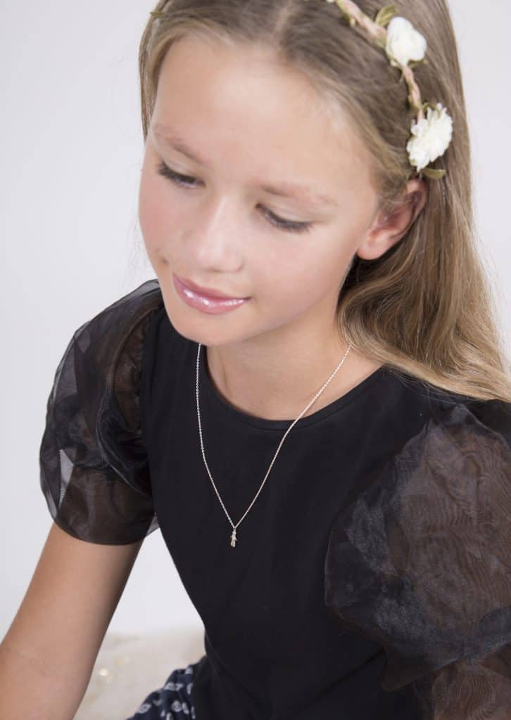 My daughter wearing the silver Worry Doll necklace with a flower headband