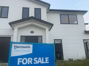 For sale sign outside a suburban family home, reflecting housing uncertainty and rental stress.